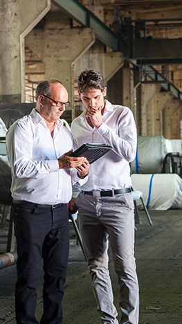 two businessmen observing an ipad in a warehouse