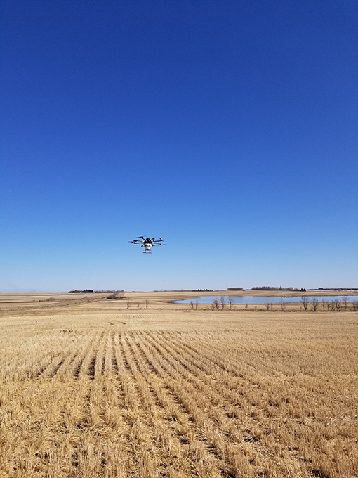Drone flying above a field, seen from afar