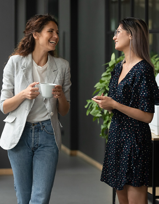 two women smiling and talking in an office