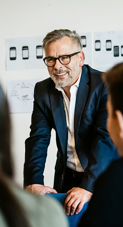 man in a meeting, smiling while listening to others