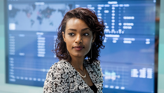 Woman standing in front of screen full of data, looking to the side