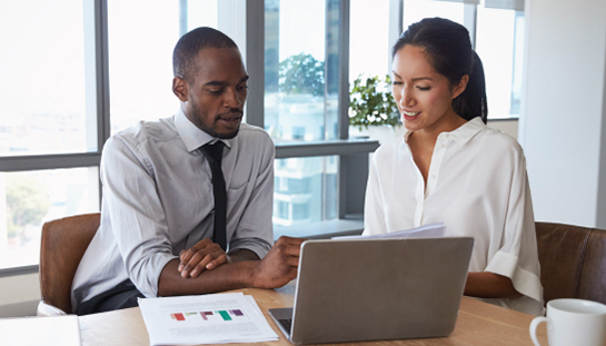 two people in a meeting, working on a computer