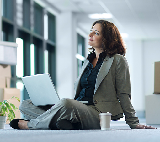 businesswoman sitting cross-legged with a laptop on her legs