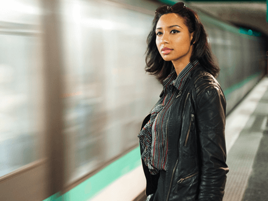 woman next to a subway, watching as it passes by