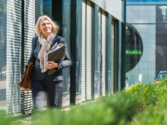 woman walking next to a building with plants 