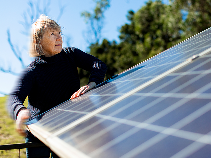 woman looking at a solar panel in a field
