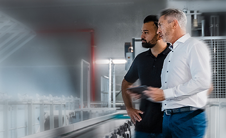 two men in a factory looking at conveyor belt