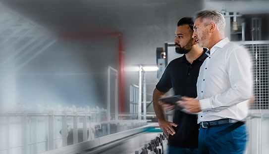 two men in a factory looking at conveyor belt