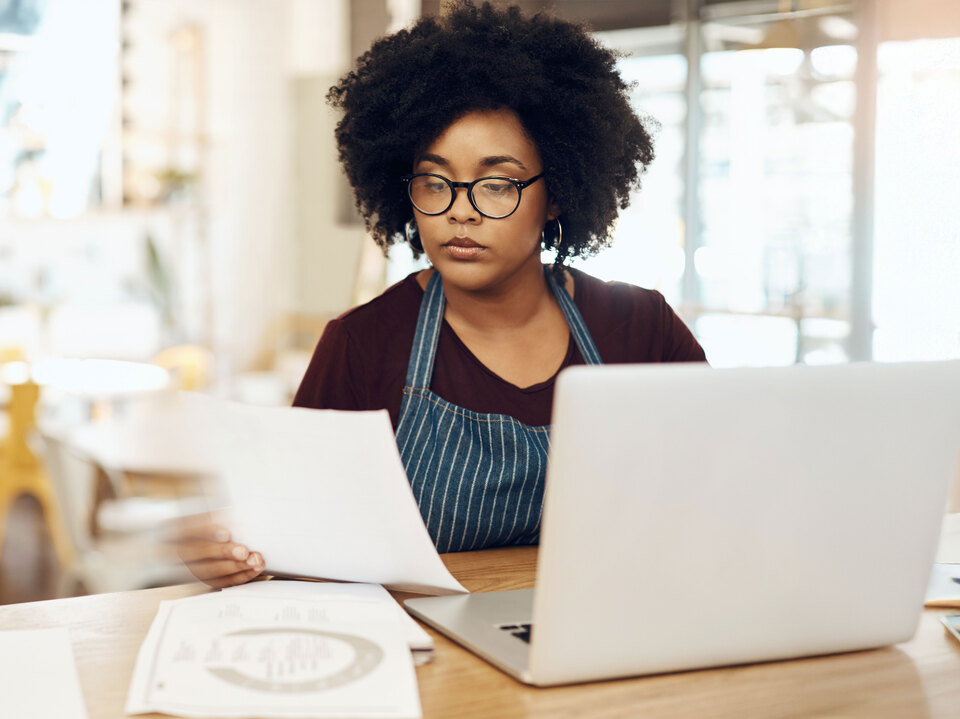 Woman analyzing data on paper and laptop